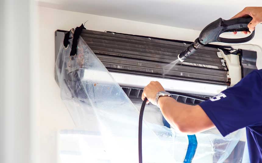 about-feature - technician cleaning air conditioner with wash bag and jet spray